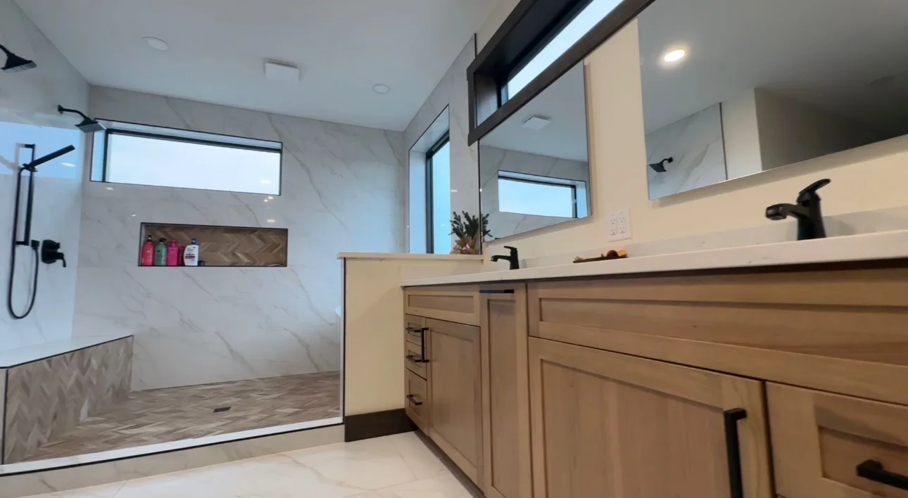Finished bathroom with a glass shower and wood double vanity