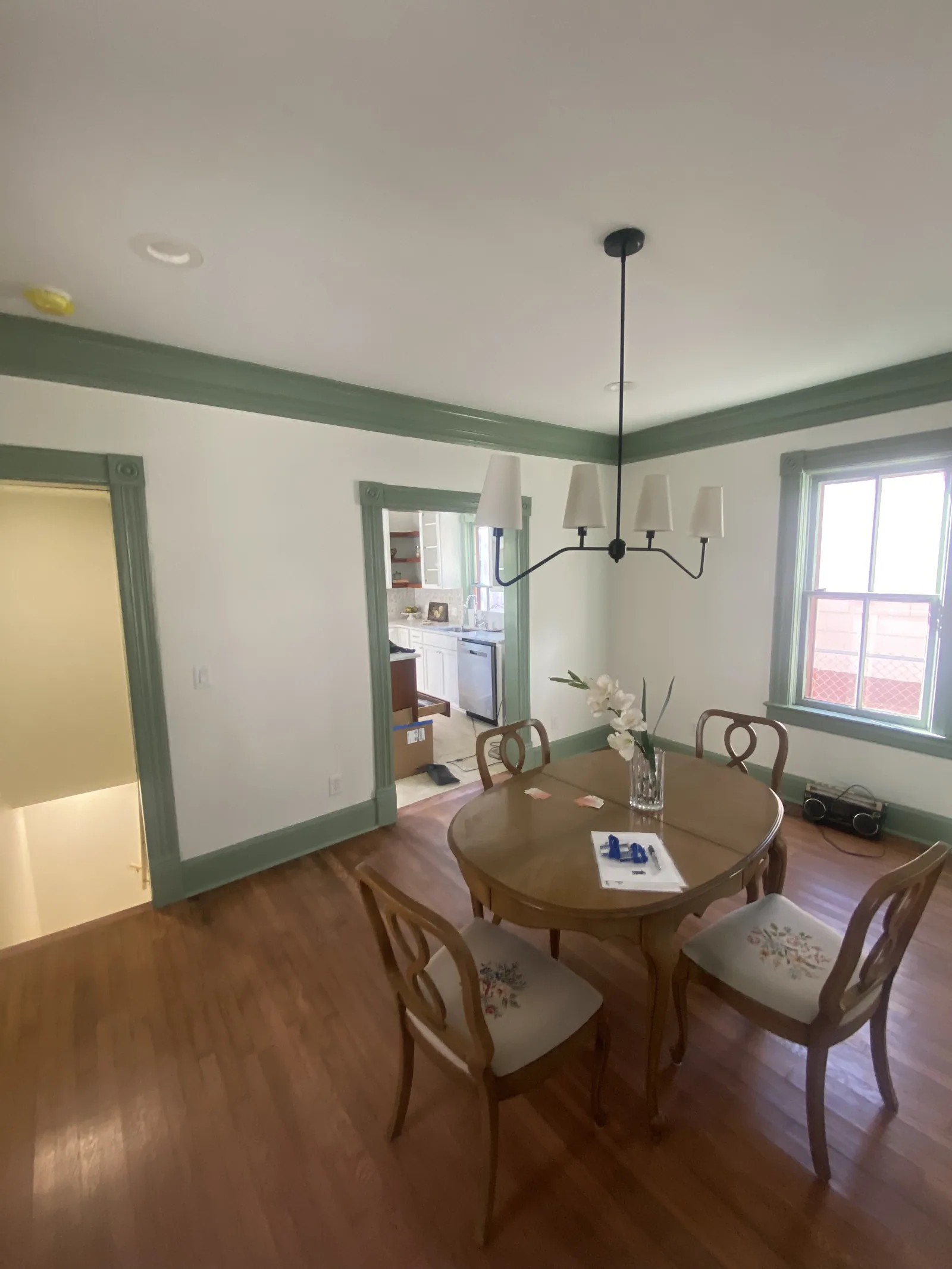 Dining room in the historic Des Moines home with green trim, wood flooring and a pendant light