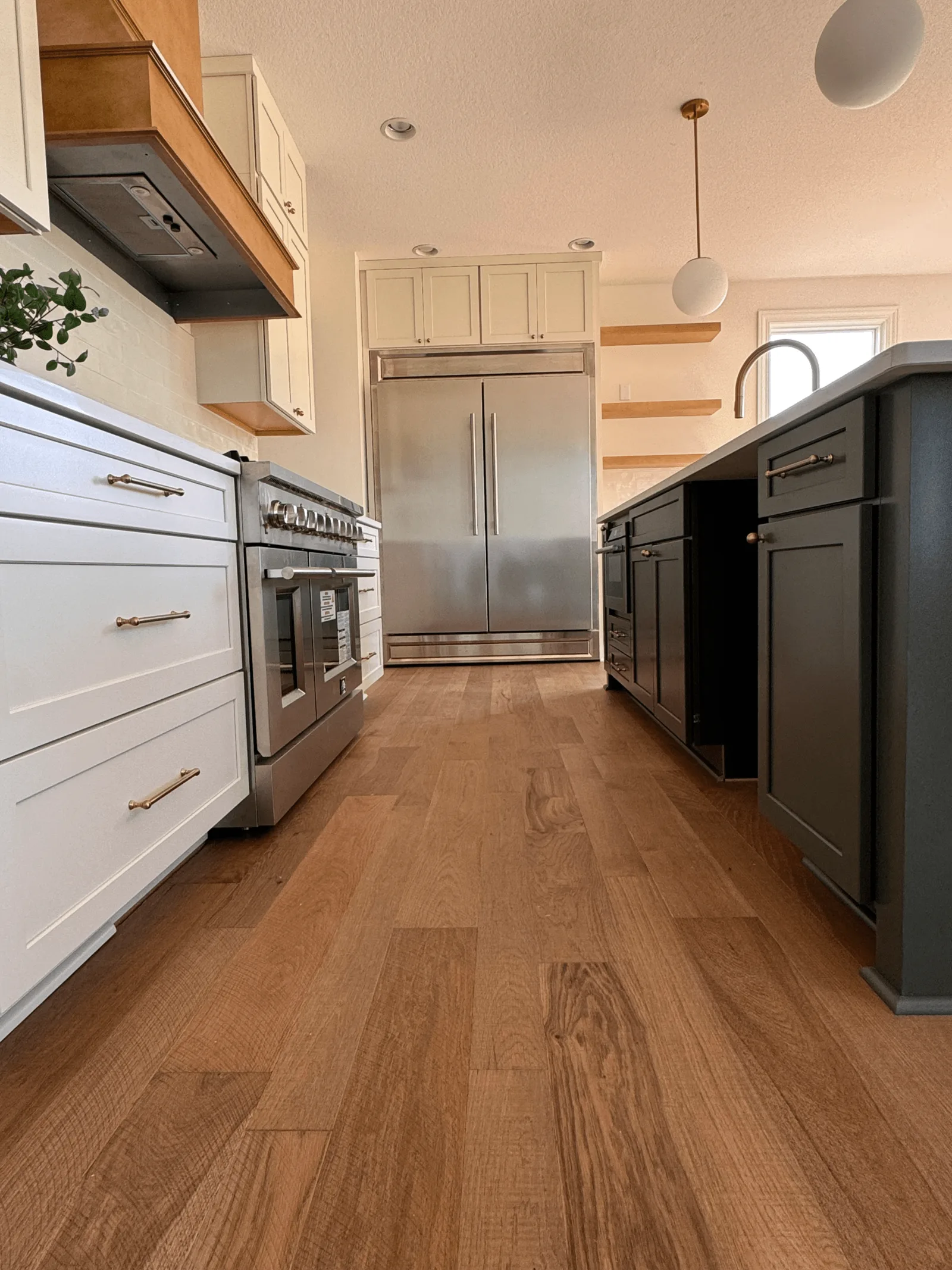 Finished kitchen with white cabinets, a dark island and wood flooring
