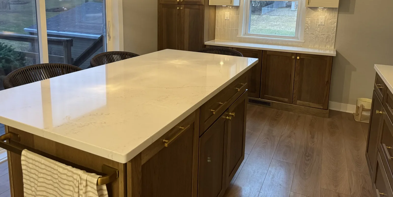 Completed kitchen with a quartz island, wood cabinets and brass hardware