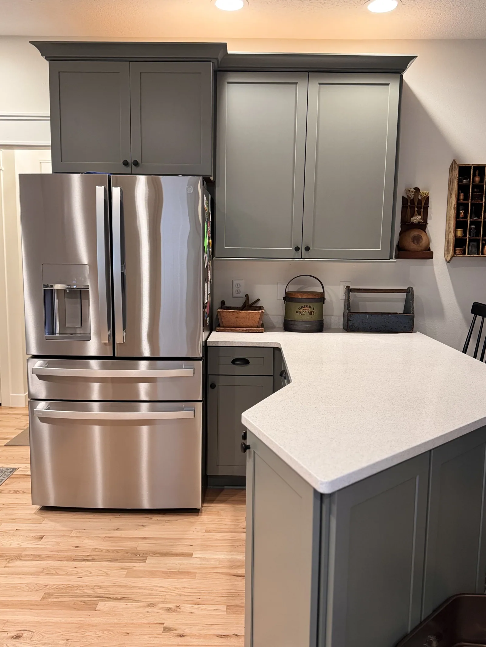 Finished kitchen with sage cabinets, a light countertop and wood flooring