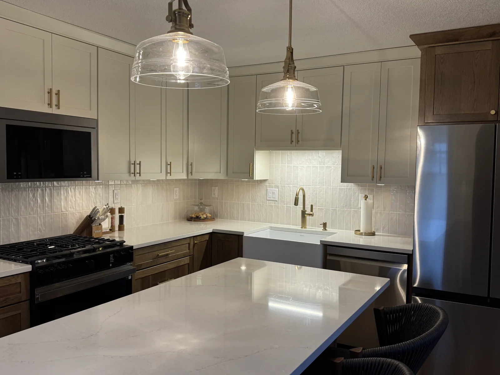 Finished two-tone kitchen with a quartz island, glass pendant lights and brass fixtures